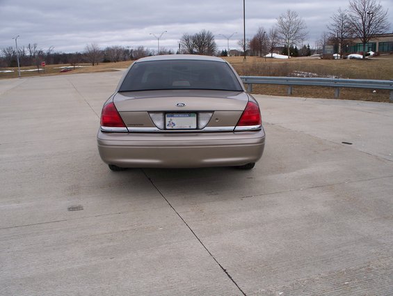 Rear view of a tan 2007 Ford Crown Victoria parked on concrete