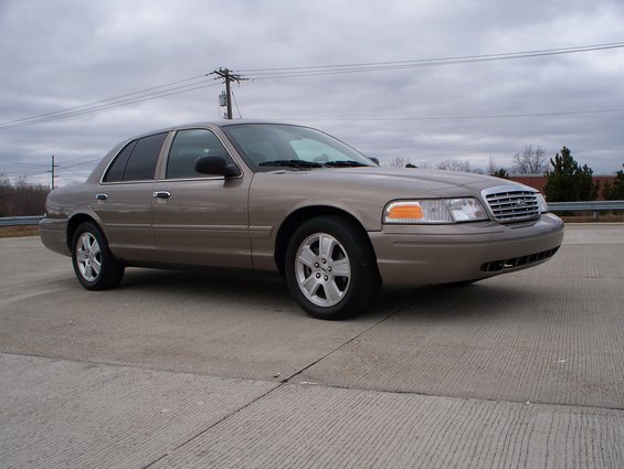 Tan 2007 Ford Crown Victoria parked on concrete with a cloudy sky