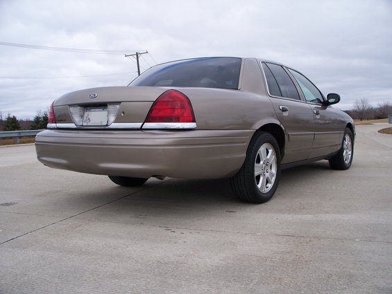 Tan 2007 Ford Crown Victoria parked on concrete with a cloudy sky
