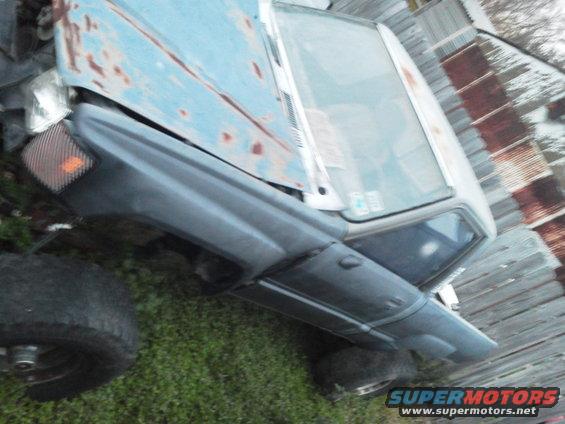 1988 Toyota Hilux truck, rusted blue hood, dark gray fender, parked on grass