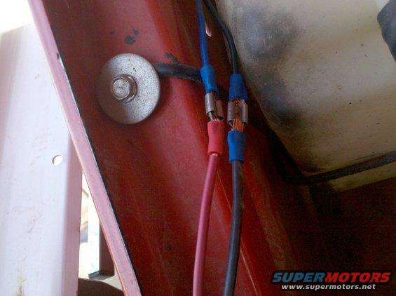 Crimped electrical wires in red and blue connectors attached to a red surface