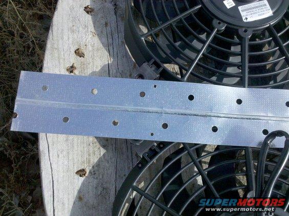 two electric fans and a metal mounting bracket on a wooden surface