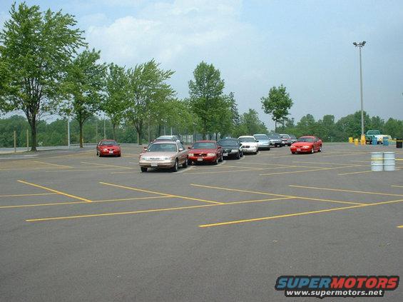 Parking lot with several cars including a 2000 Ford Crown Victoria, red Ford Mustang, and other sedans