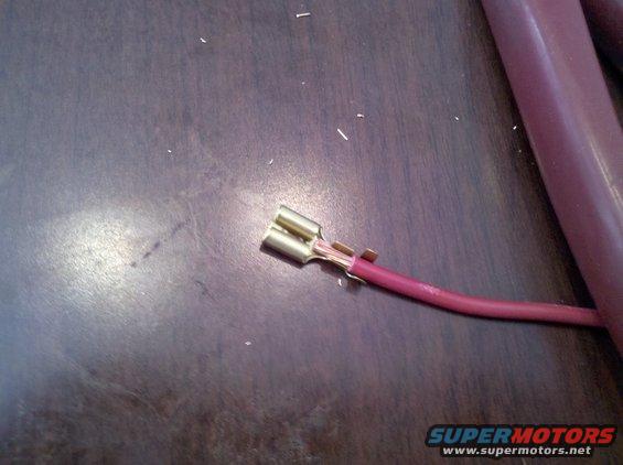 Wire with a brass female spade connector attached, lying on a dark surface