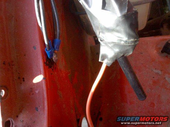 Close-up of electrical wiring with blue connectors and black tape on a red surface