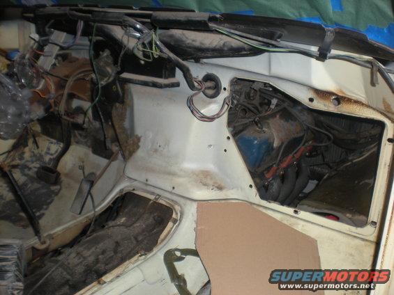 Vehicle firewall area with exposed wiring and engine components. Some insulation is visible