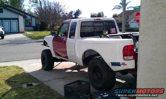 White and maroon Ford Ranger pickup truck with lifted suspension and off-road tires, parked on a driveway