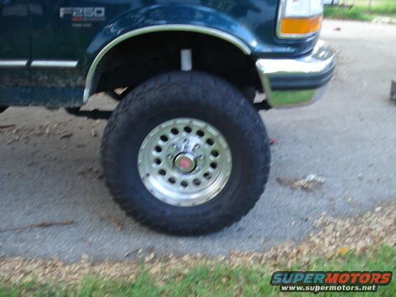 Close-up of a 1994 Ford F-250's front wheel and fender. The truck is dark green