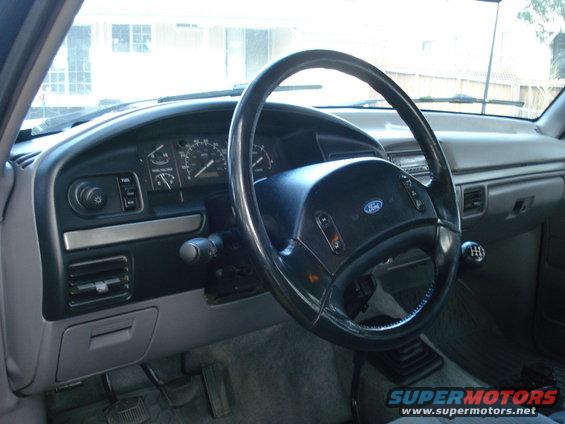 Gray dashboard and steering wheel of a Ford truck, showing the instrument cluster and gear shift