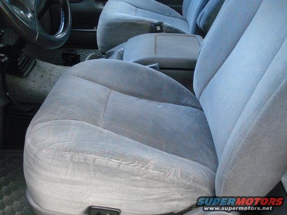 Close-up of light blue fabric seats and center console in a truck. Steering wheel visible on left
