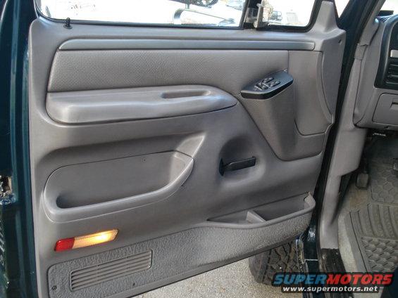 Green truck's gray interior door panel with power window controls and a red and amber reflector light