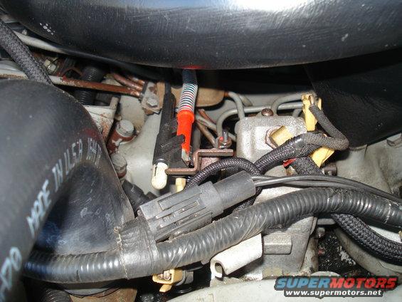Close-up of engine bay with hoses, wires, and metal components visible. Some text on a hose reads 'MADE IN USA'