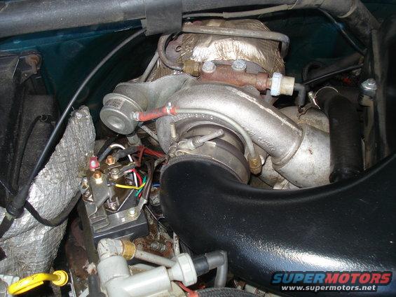 Close-up of a turbocharger, exhaust manifold, and wiring harness in an engine bay