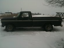 Black 1977 Ford F-150 pickup truck, side view, in snow