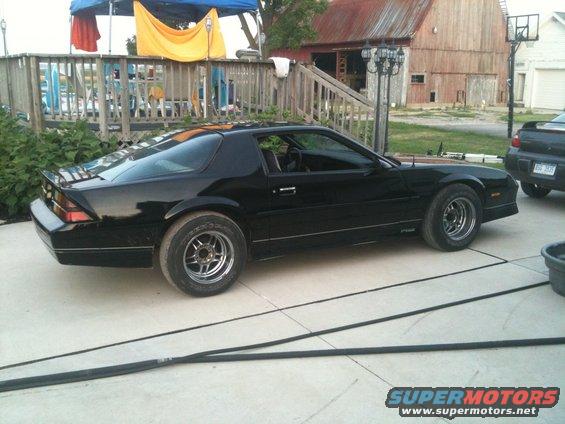 Black 1988 Chevrolet Camaro parked on concrete driveway, side view