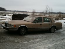 Tan 1990 Lincoln Town Car parked outside on a cloudy day