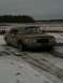 1990 Lincoln Town Car - A damaged brown sedan sits in a field covered with patches of snow and ice.