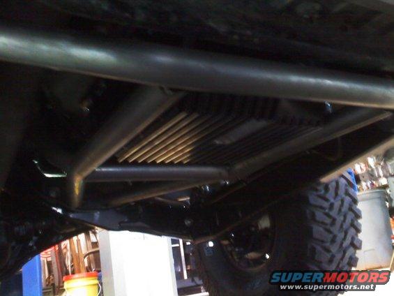 Undercarriage of a modified SUV with a large tire and visible roll cage tubing