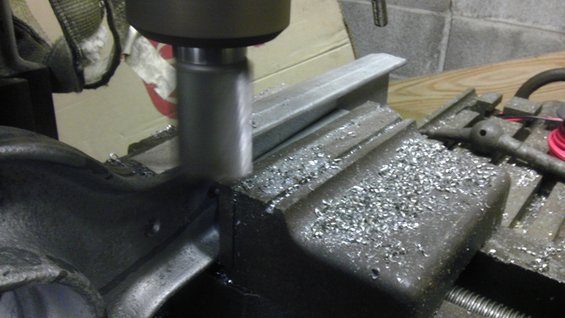 Milling machine cutting metal workpiece held in a vise, with metal shavings scattered