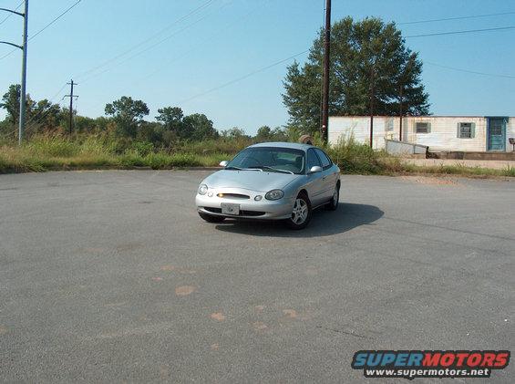 Silver sedan parked in a lot, building and trees in background
