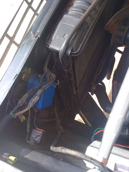 Engine bay with radiator, blue electrical component, and wiring
