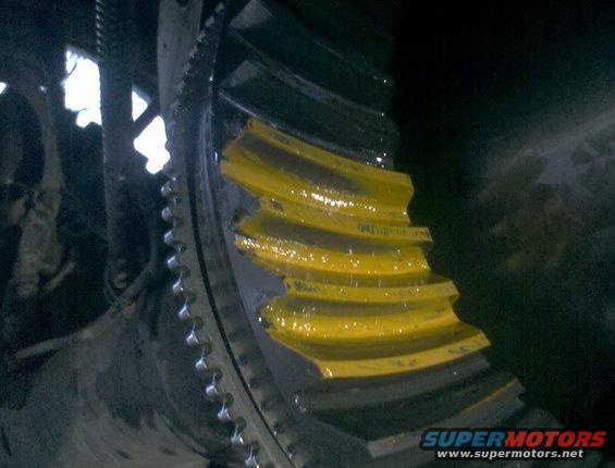 Close-up of yellow-coated differential gears with teeth visible. Some text is on the gears