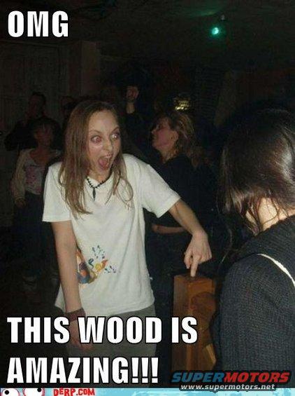 Woman with wide eyes pointing at a wooden object in a dimly lit room