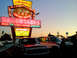 1994 Ford Bronco - Two SUVs are parked in front of a vintage neon sign for Angelo's Hamburgers, advertising drive-thru service and draft beers.