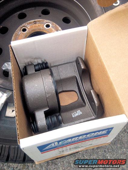 Cardone brake caliper in box, next to a spare tire