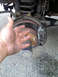 1994 Ford Bronco - A hand is placed over the brake rotor and caliper of a vehicle's rear axle.