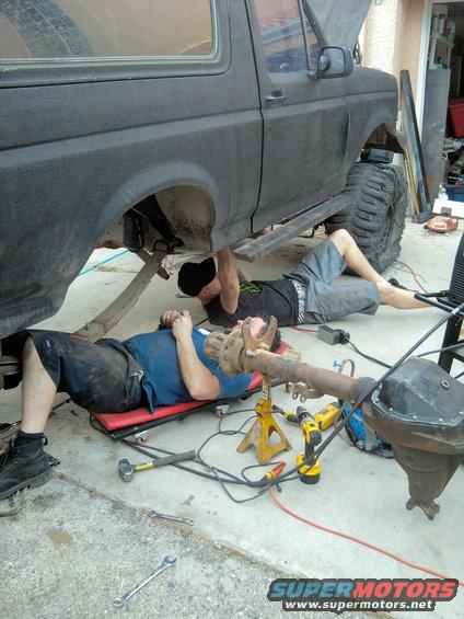 Black 1994 Ford Bronco side view with two men working on its undercarriage