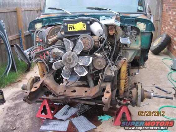 1979 Ford Bronco engine bay disassembled, front suspension on jack stands. Green body panels visible