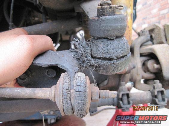 Close-up of a damaged vehicle ball joint with torn rubber boot and cracked bushings