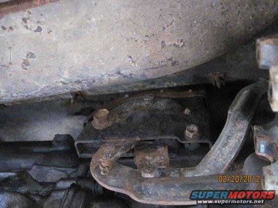 Underside of a vehicle showing rusty metal brackets and pipes. Date stamp reads 02/20/2012