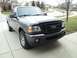 2011 Ford Ranger - Gray Ford Ranger pickup truck parked on a concrete driveway in front of houses.