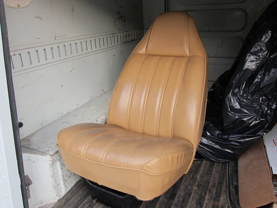 Tan vinyl bucket seat inside a cargo van with tie-down rails on the wall