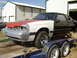 1987 Ford Mustang - A 1987 Ford Mustang is on a trailer, showing its unfinished state with mismatched paint and missing headlights.