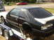 1987 Ford Mustang - A black and white 1987 Ford Mustang coupe is seen on a trailer, missing its rear wheels and with some body damage.