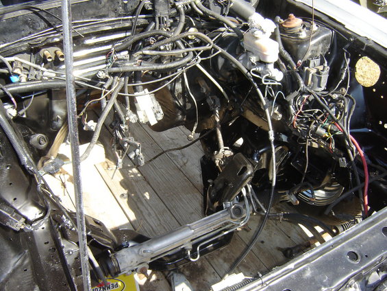 Car's engine bay, engine removed, showing wiring and frame