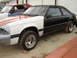 1987 Ford Mustang - A two-tone 1987 Ford Mustang coupe is shown in a side profile, appearing to be under repair.