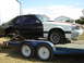 1987 Ford Mustang - A two-tone 1987 Ford Mustang coupe, partially disassembled and loaded onto a trailer for transport.