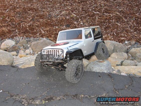 Silver RC Jeep Wrangler on rocks and cracked asphalt