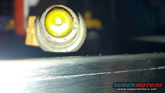 Close-up of a yellow automotive sensor with a metal housing