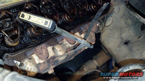 Engine bay showing valve cover, spark plugs, and an oil dipstick with "ENGINE OIL" text