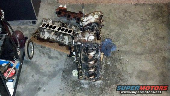 Disassembled engine block and intake manifold on a concrete floor