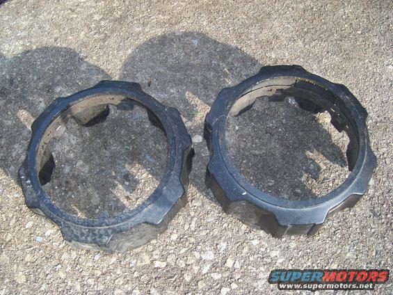 Two black plastic rings with gear-like edges on a gravel surface