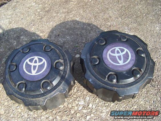 Two black Toyota wheel center caps with purple accents and the Toyota logo