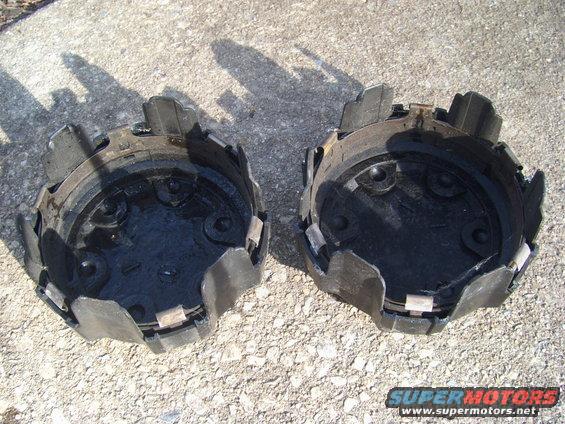 Two black plastic hubcaps with clips, lying on concrete