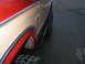 1984 Ford Bronco - Close-up of the side of a lifted 1984 Ford Bronco, showing its two-tone paint and off-road tires.