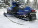 1987 Polaris Indy 600 - A blue Yamaha snowmobile sits in a snowy landscape, with trees in the background.